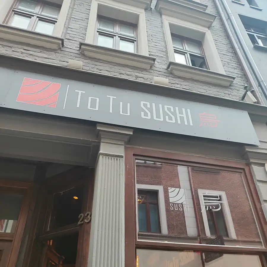 Szyld ToTu Sushi nad wejściem do kamienicy przy Szewskiej 23